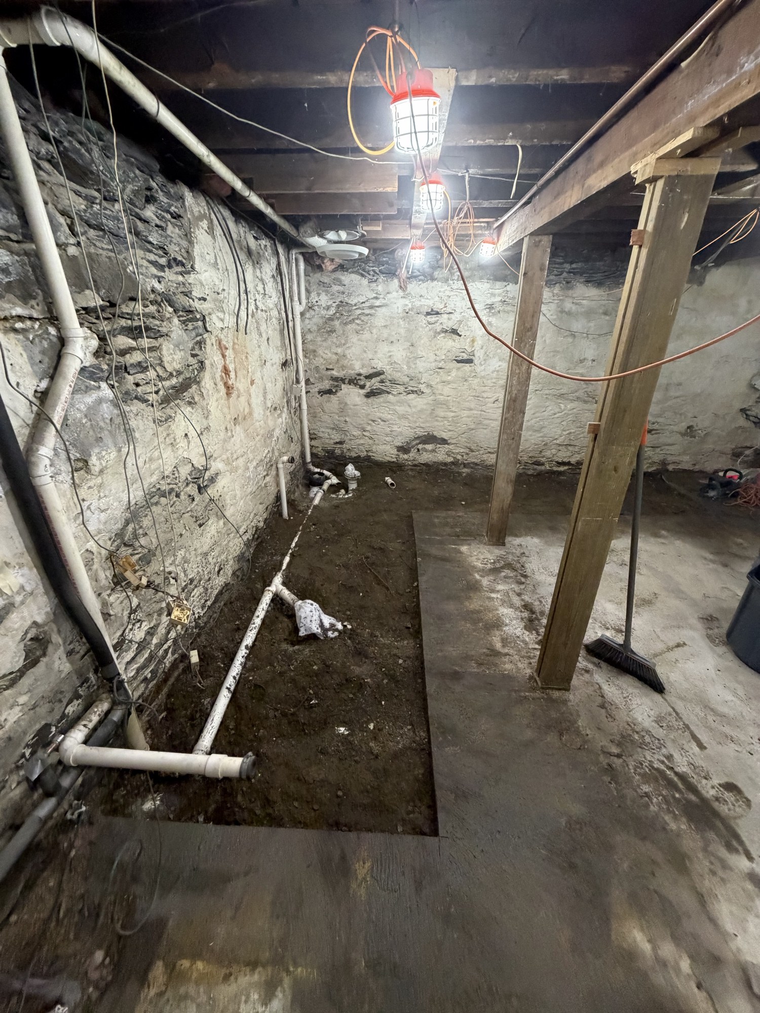 Basement crawl space with footing trench dug and plumbing roughed in