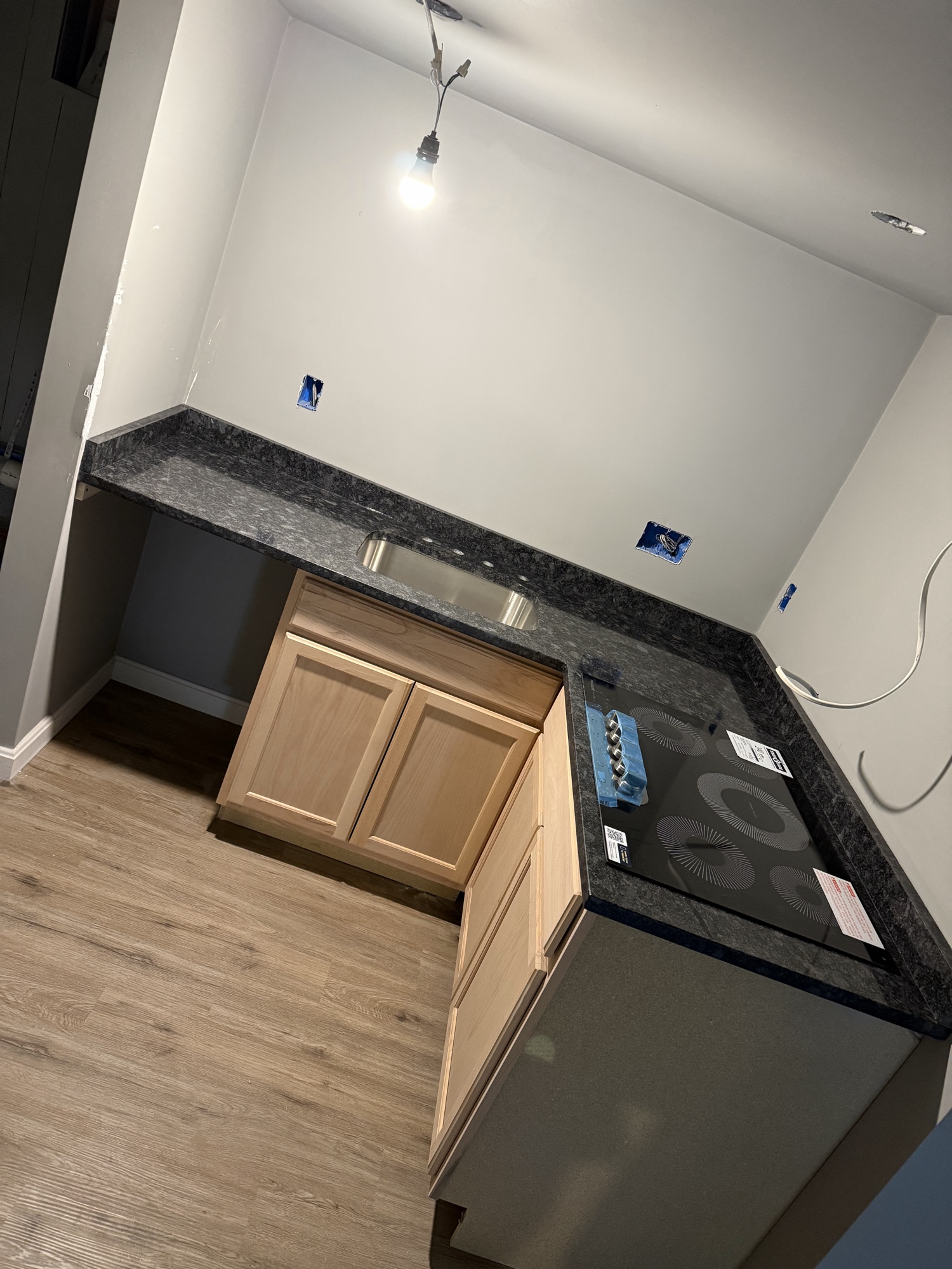 Finished basement kitchenette with granite countertop, cooktop, and cabinets